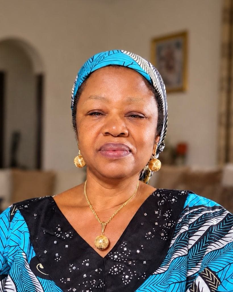 Mrs Egbo seated at home, wearing gold earrings and a blue print headwrap